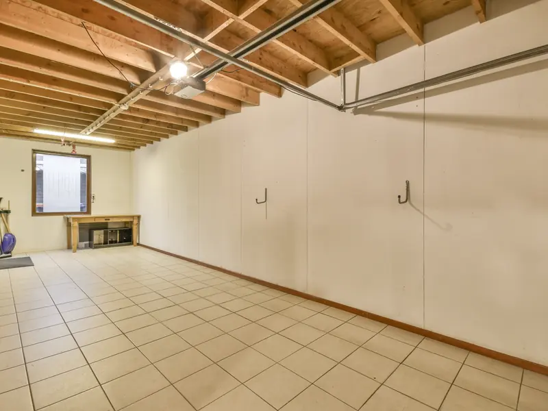 Unfinished basement with bare wood joists and exposed pipes before ceiling painting in Turnersville