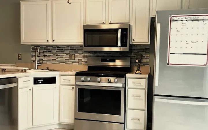 Kitchen cabinets painted white with a tile backsplash and stainless appliances, cabinet painting in South Jersey