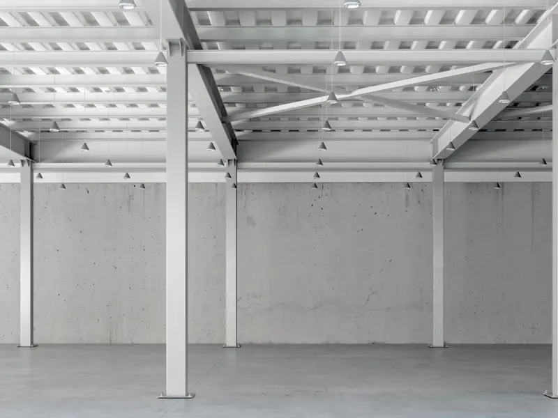 Open lower level with steel beams, columns, and deck ceiling sprayed bright white
