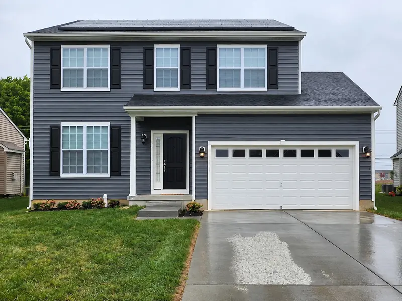 Charcoal gray colonial with black shutters, white trim, and a white two-car garage door