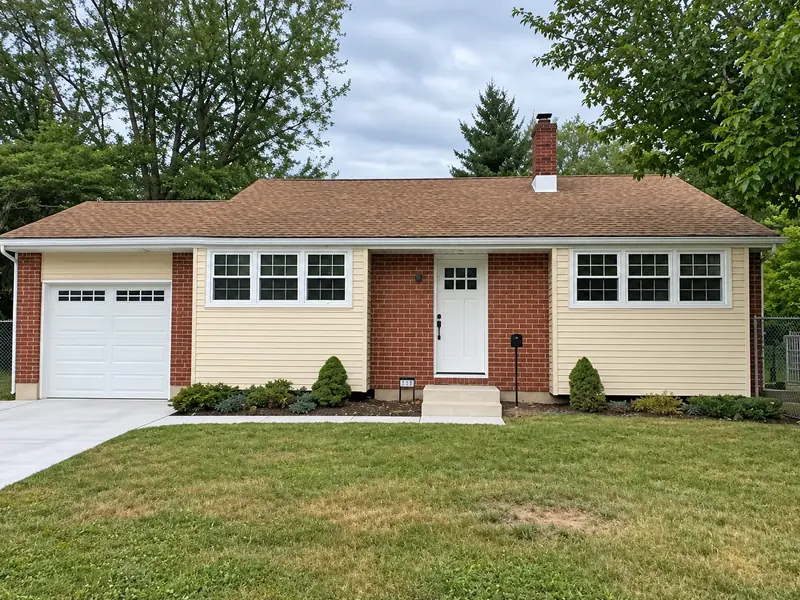 Brick rancher with cream painted siding, white trim, and a white garage door