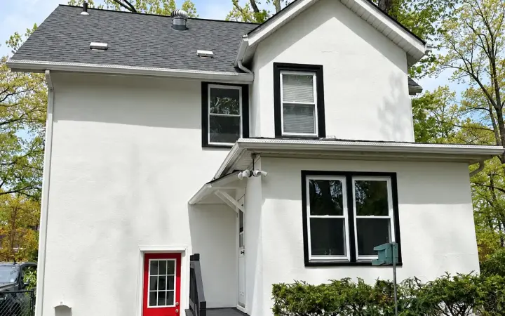 Two-story stucco home painted bright white with black window trim and a red door, exterior painting in South Jersey