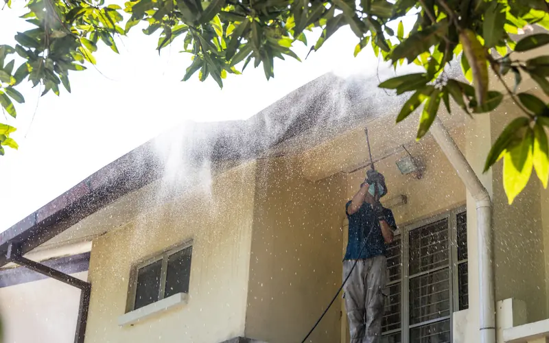 Technician washing the front siding of a Sewell home