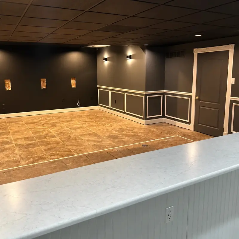 Finished basement painted charcoal with white picture-frame wainscoting and a dark ceiling