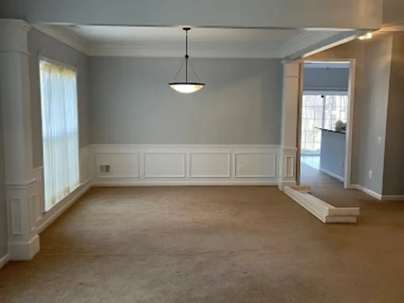 Dining room painted light gray with white wainscoting, columns, and crown molding