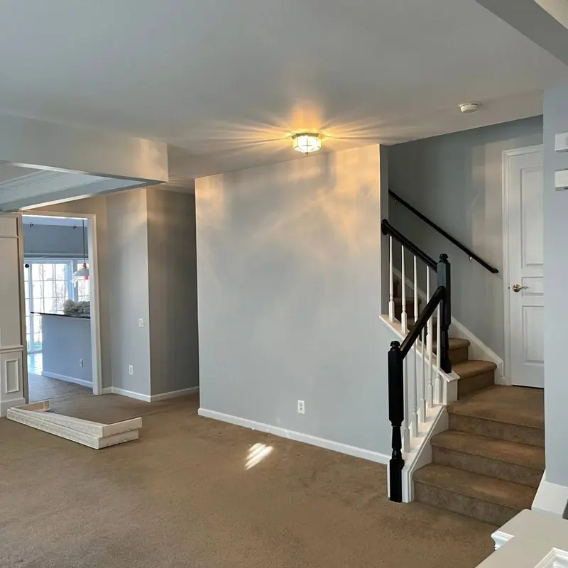 Foyer and stairway painted soft gray with white trim and a black-stained handrail