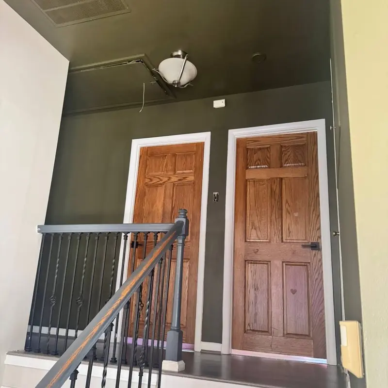 Stair landing painted deep olive green with white door casings and natural oak doors