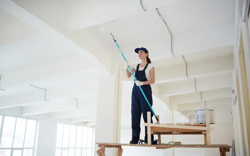 Rolling paint onto an exposed basement ceiling in Washington Township NJ