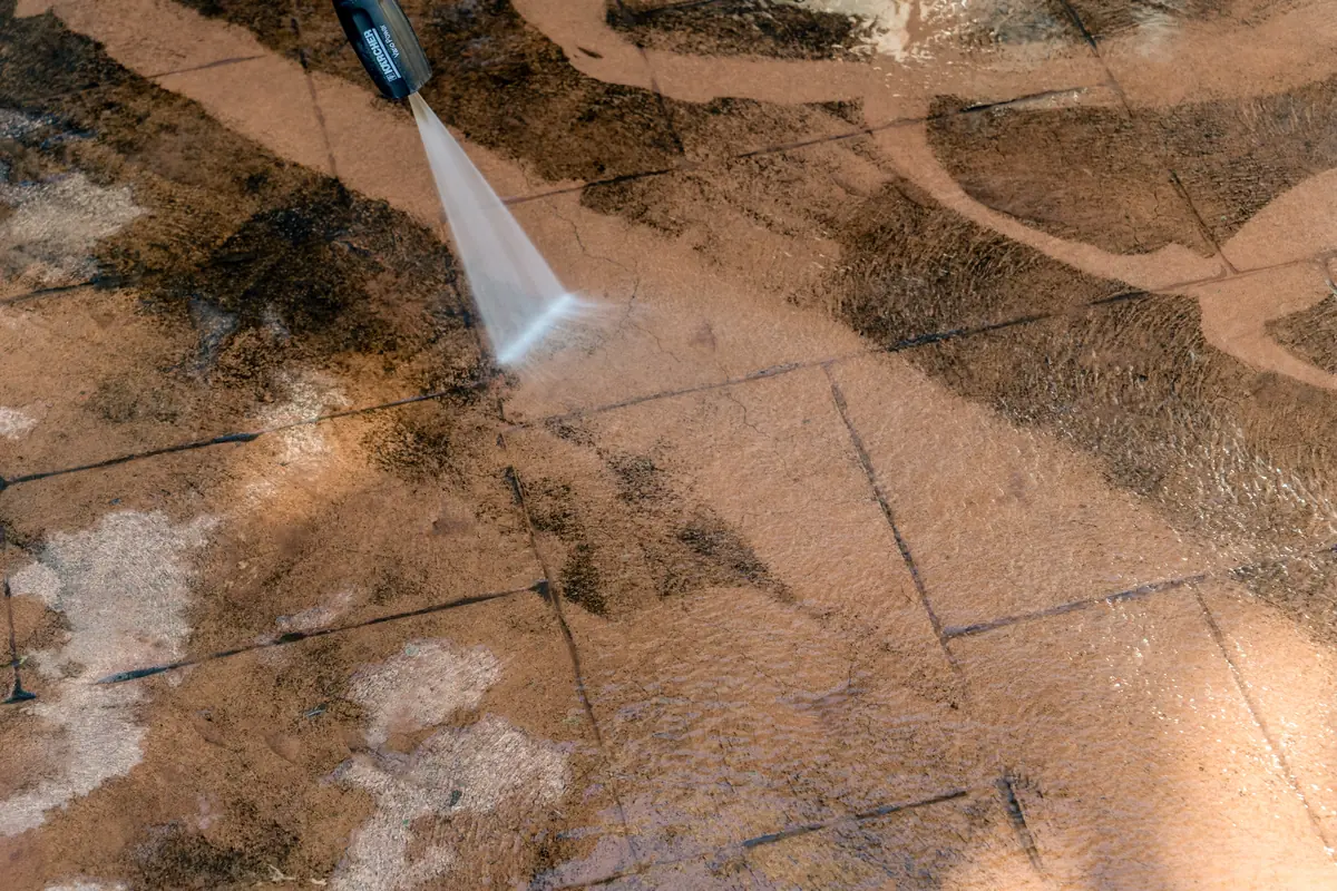 Pressure washing concrete pavers on a Washington Township walkway, cleaned section next to the untouched section
