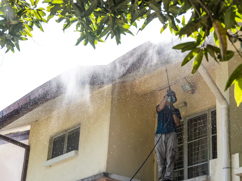 Technician washing the front siding of a Sewell home on a sunny day