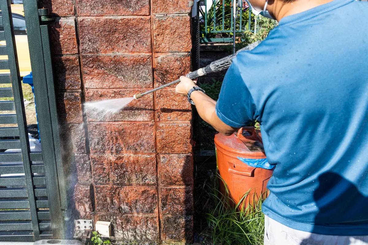 Low-pressure wand removing green algae and moss from a home exterior wall in Washington Township